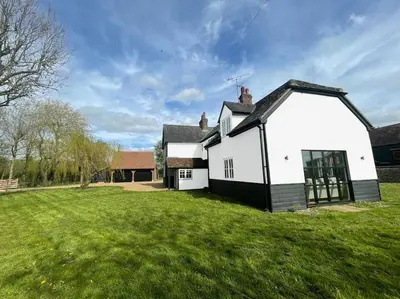 a white and black house with a grass yard at Mallards - English Countryside Retreat in Lindsell