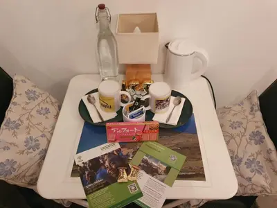a tray with cups and a bottle on a bed at The Pringle Inn in Great Baddow