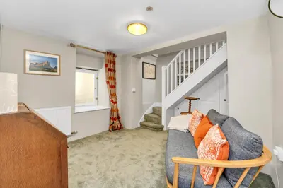 a living room with a couch and a staircase at Charming cottage in the centre of town in Bury Saint Edmunds