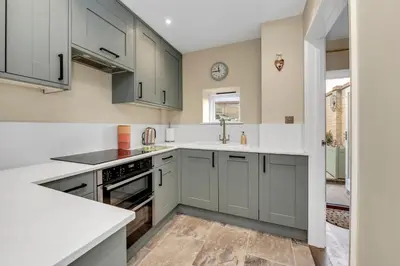 a kitchen with gray cabinets and white countertops at Charming cottage in the centre of town in Bury Saint Edmunds