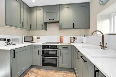 a kitchen with white cabinets and a sink at Charming cottage in the centre of town in Bury Saint Edmunds