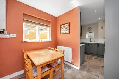 a dining room with orange walls and a wooden table at Charming cottage in the centre of town in Bury Saint Edmunds