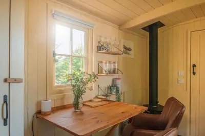 a room with a wooden table and a window at Hill Top Hideaway Shepherds Hut with Hot Tub in Woodham Mortimer