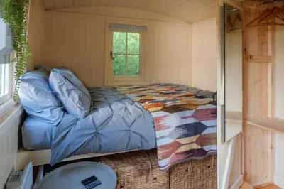 a bedroom with a bed in a small room at Hill Top Hideaway Shepherds Hut with Hot Tub in Woodham Mortimer