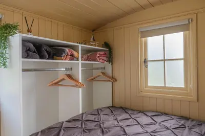 a room with a window and shelves with shoes at Hill Top Hideaway Shepherds Hut with Hot Tub in Woodham Mortimer
