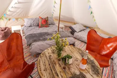 a room with a table and a bed in a tent at Hill Top Hideaway Shepherds Hut with Hot Tub in Woodham Mortimer