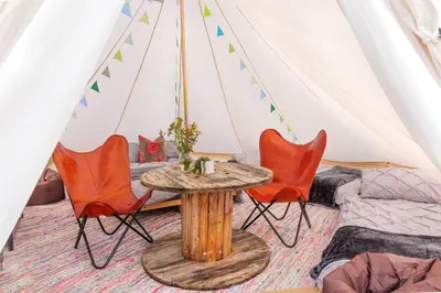 a room with a table and chairs in a tent at Hill Top Hideaway Shepherds Hut with Hot Tub in Woodham Mortimer