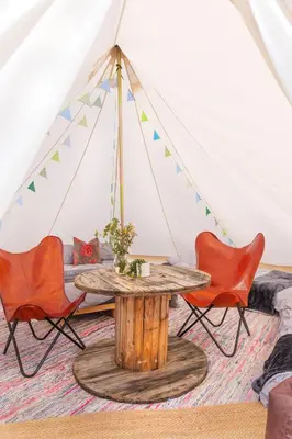 a room with a table and chairs in a tent at Hill Top Hideaway Shepherds Hut with Hot Tub in Woodham Mortimer