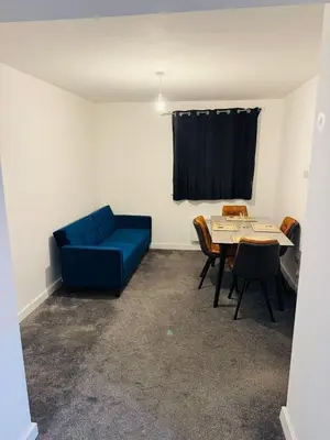 a living room with a blue couch and a table at Canvey Stay Entire Flat in Canvey Island