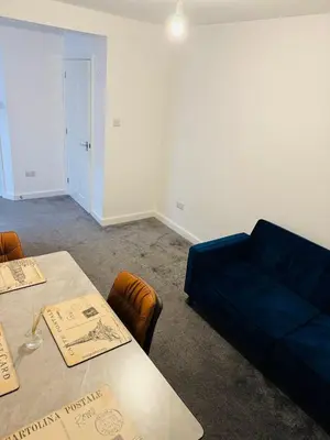 a living room with a blue couch and a table at Canvey Stay Entire Flat in Canvey Island