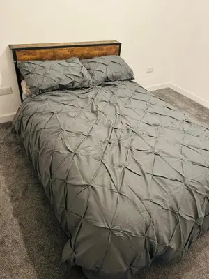 a large bed with a gray comforter and pillows at Canvey Stay Entire Flat in Canvey Island