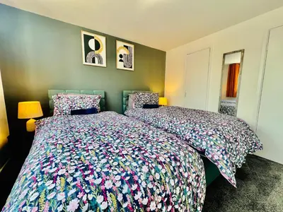 a bedroom with a large bed with a colorful bedspread at 4 Bedroom House in the Heart of Basildon 2 mins to Town Center I Weekly or Monthly Stay Offer I Free Parking I Sleeps 7 in Basildon