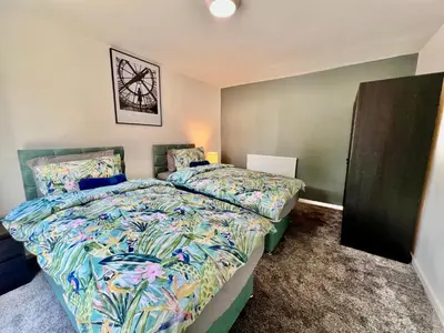 a bedroom with two beds and a picture on the wall at 4 Bedroom House in the Heart of Basildon 2 mins to Town Center I Weekly or Monthly Stay Offer I Free Parking I Sleeps 7 in Basildon