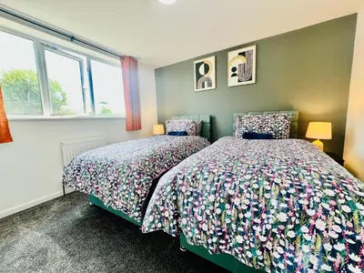 a bedroom with two beds and two windows at 4 Bedroom House in the Heart of Basildon 2 mins to Town Center I Weekly or Monthly Stay Offer I Free Parking I Sleeps 7 in Basildon