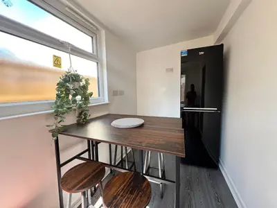 a small kitchen with a table and a refrigerator at 4 Bedroom House in the Heart of Basildon 2 mins to Town Center I Weekly or Monthly Stay Offer I Free Parking I Sleeps 7 in Basildon