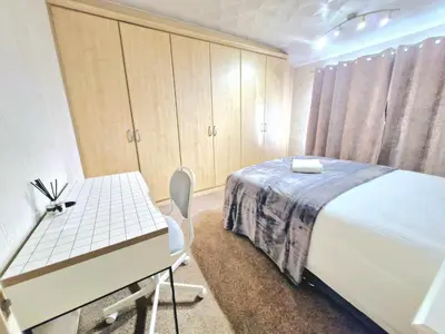 a bedroom with a bed and a desk and a table at Cosy Luxurious Large 3 bedroom house, free parking, free WiFi in Havering atte Bower
