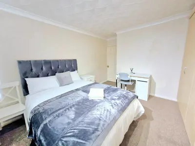 a bedroom with a large bed and a desk at Cosy Luxurious Large 3 bedroom house, free parking, free WiFi in Havering atte Bower