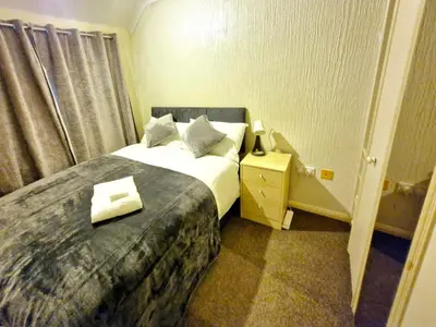 a bedroom with a bed with a book on it at Cosy Luxurious Large 3 bedroom house, free parking, free WiFi in Havering atte Bower