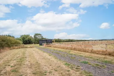a dirt road in a field with a fence at River Retreat, Aldeburgh in Aldeburgh