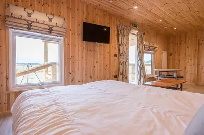 a bedroom with a large white bed and a television at River Retreat, Aldeburgh in Aldeburgh
