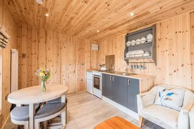 a kitchen with wooden walls and a table and chairs at River Retreat, Aldeburgh in Aldeburgh