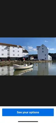 a small boat sitting in the water next to buildings at Sun lane cottage in Woodbridge