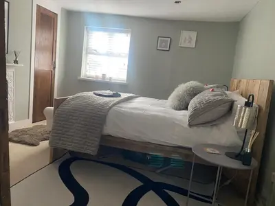 a bedroom with a bed with a table and a window at Sun lane cottage in Woodbridge
