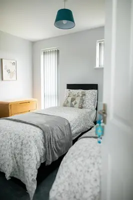 a bedroom with two beds and a lamp at Lovely 3 Bedroom House in Chelmsford in Chelmsford