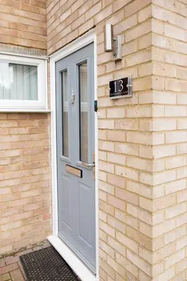 a door on a brick building with a clock on it at Lovely 3 Bedroom House in Chelmsford in Chelmsford
