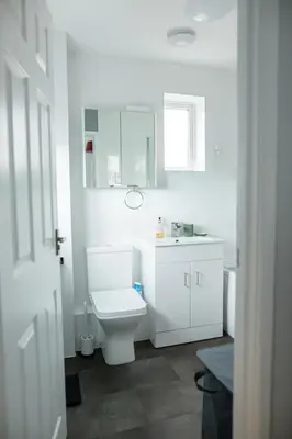 a white bathroom with a toilet and a sink at Lovely 3 Bedroom House in Chelmsford in Chelmsford
