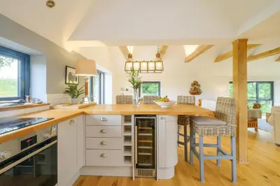 a kitchen with white cabinets and wooden countertops at Sandown in Snape
