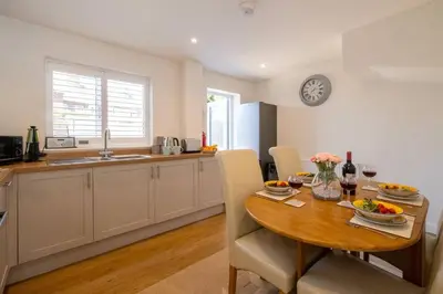 a kitchen and dining room with a wooden table with chairs at 1 Buxlow Cottages in Aldringham
