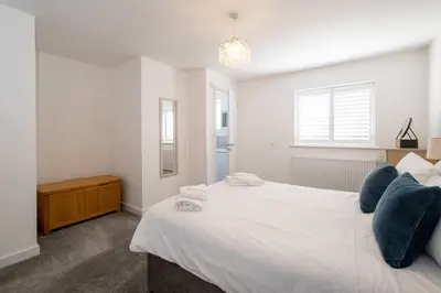 a bedroom with a large white bed with blue pillows at 1 Buxlow Cottages in Aldringham