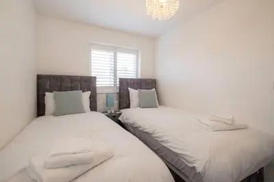 two twin beds in a bedroom with a chandelier at 1 Buxlow Cottages in Aldringham