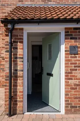 an open door to a brick house with a green door at 1 Buxlow Cottages in Aldringham