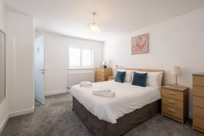 a bedroom with a bed with white sheets and blue pillows at 1 Buxlow Cottages in Aldringham
