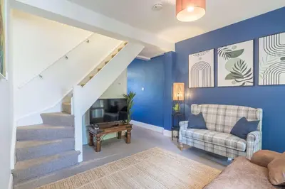 a living room with blue walls and a staircase at Stylish 2-Bedroom House in the Heart of Cambridge in Cambridge