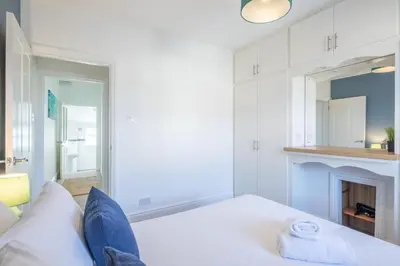 a white room with a bed and a fireplace at Stylish 2-Bedroom House in the Heart of Cambridge in Cambridge