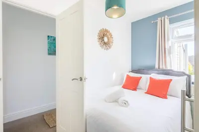a bedroom with a white bed with orange pillows at Stylish 2-Bedroom House in the Heart of Cambridge in Cambridge