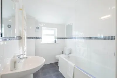 a white bathroom with a tub and a sink at Stylish 2-Bedroom House in the Heart of Cambridge in Cambridge