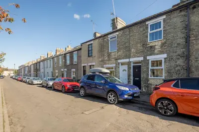 a row of cars parked in front of a brick building at Stylish 2-Bedroom House in the Heart of Cambridge in Cambridge