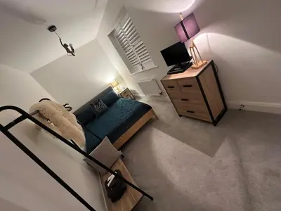 a living room with a blue couch and a dresser at Cosy room in Great Bromley