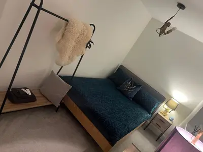 a bedroom with a bed with a green sheets and a lamp at Cosy room in Great Bromley