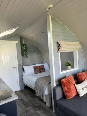 a bedroom with a bed and a mirror and a couch at Windmill Glamping Pod with hot tub - The Snug in Swavesey