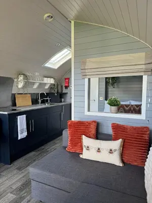 a living room with a couch and a kitchen at Windmill Glamping Pod with hot tub - The Snug in Swavesey
