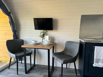 a small table with two chairs and a tv at Windmill Glamping Pod with hot tub - The Snug in Swavesey