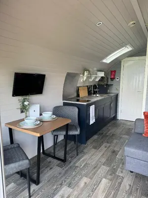 a kitchen and dining area in a trailer with a table and chairs at Windmill Glamping Pod with hot tub - The Snug in Swavesey
