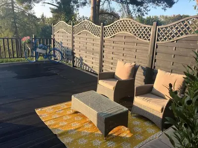 a patio with two chairs and a bench on a deck at Wood Lodge in Bungay