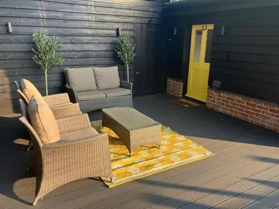 a patio with a couch and a table and a yellow door at Wood Lodge in Bungay