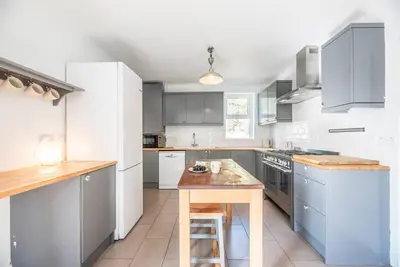 a kitchen with white appliances and a wooden table at The Red House, Leiston in Woodbridge
